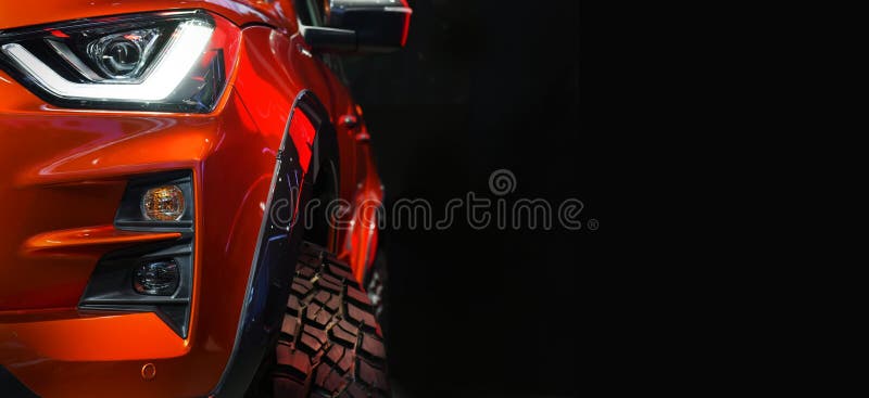 Close up detail on one of the LED headlights red Pickup Truck on black background