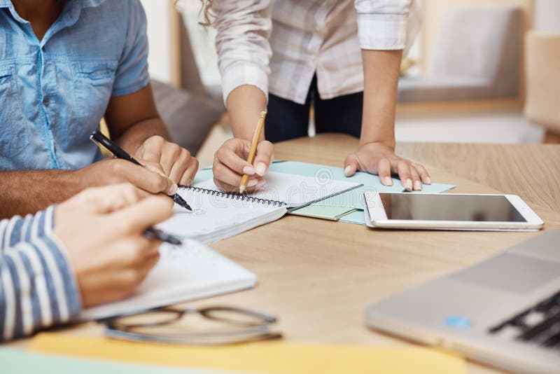 Close up detail of team working o new project in coworking space, writing ideas, looking through graphics on tablet and stock image Close up detail of team working o new project in coworking space, writing ideas, looking through graphics on tablet and stock image