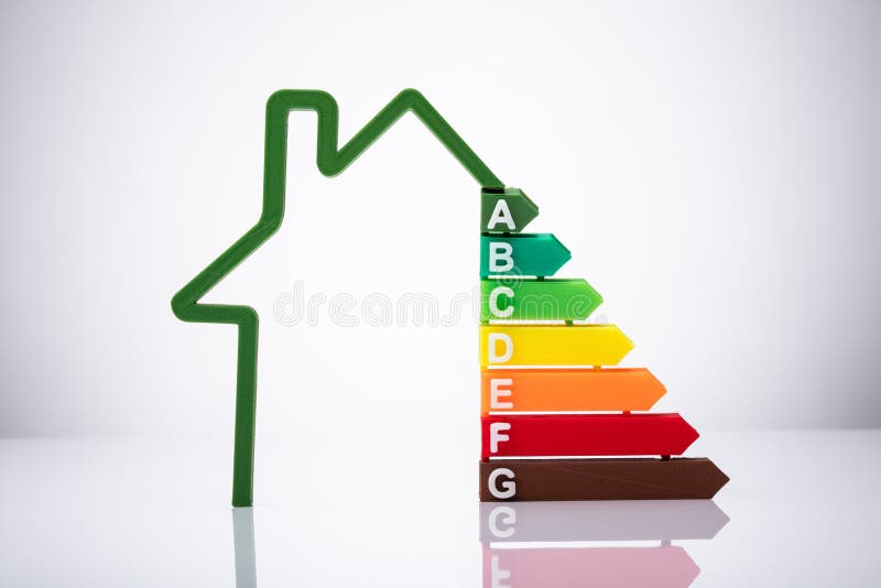 Close-up Of House Showing Energy Efficiency Rate Over Reflective Desk. Close-up Of House Showing Energy Efficiency Rate Over Reflective Desk