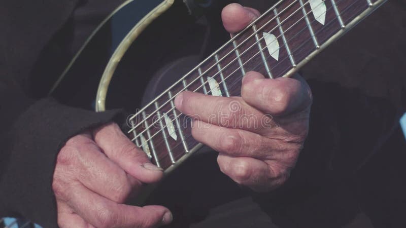 Close-up die van oude handen basgitaar spelen voorraad De oude gitarist voert masterfully melodie op basgitaar in openlucht uit stock videobeelden Close-up die van oude handen basgitaar spelen voorraad De oude gitarist voert masterfully melodie op basgitaar in openlucht uit stock videobeelden