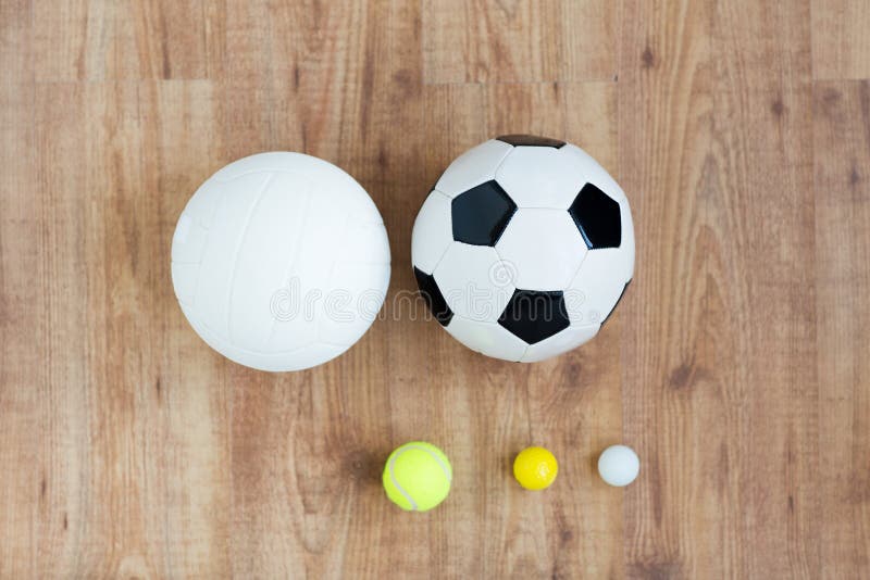 Sport, fitness, game, sports equipment and objects concept - close up of different sports balls set on wooden floor from top