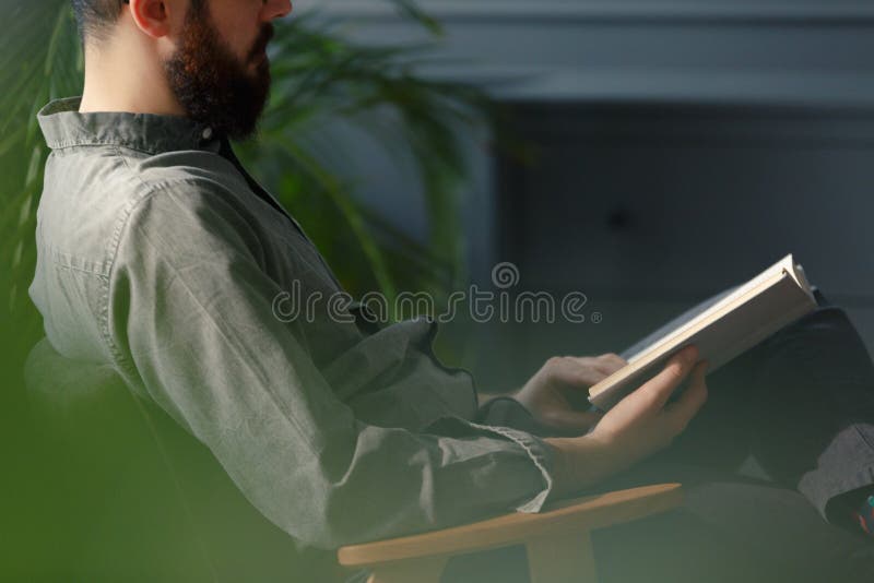 Close-up do homem com a barba no livro de leitura cinzento da camisa foto de stock Close-up do homem com a barba no livro de leitura cinzento da camisa foto de stock