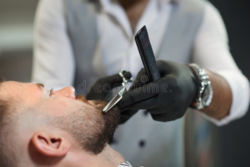 Close up do processo de cortar a barba do cliente na barbearia imagem de stock royalty free Close up do processo de cortar a barba do cliente na barbearia imagem de stock royalty free