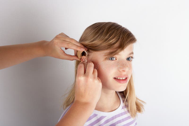 Close up of a Doctor`s hands fitting a hearing aid for a young girl
