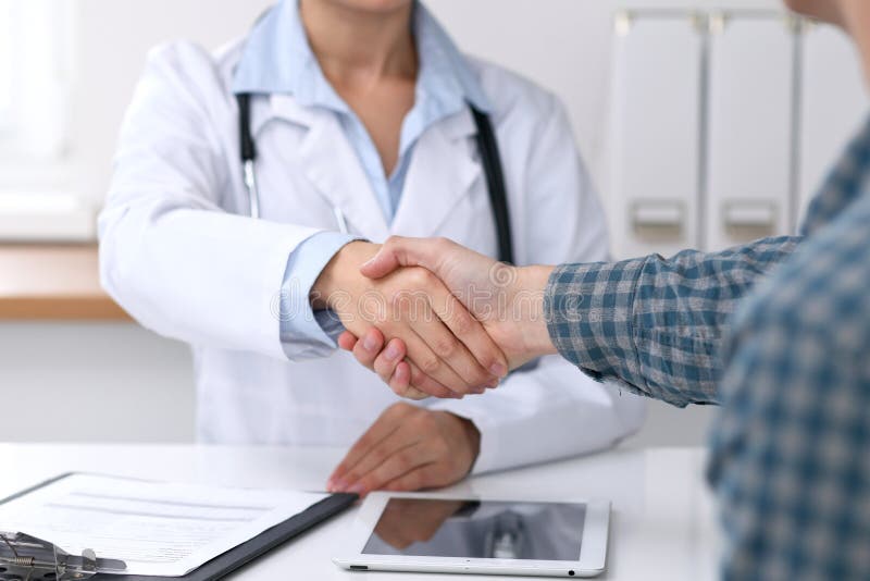 Close up of a doctor woman shaking hands with her male patient. Medicine and trust concept royalty free stock photography Close up of a doctor woman shaking hands with her male patient. Medicine and trust concept royalty free stock photography