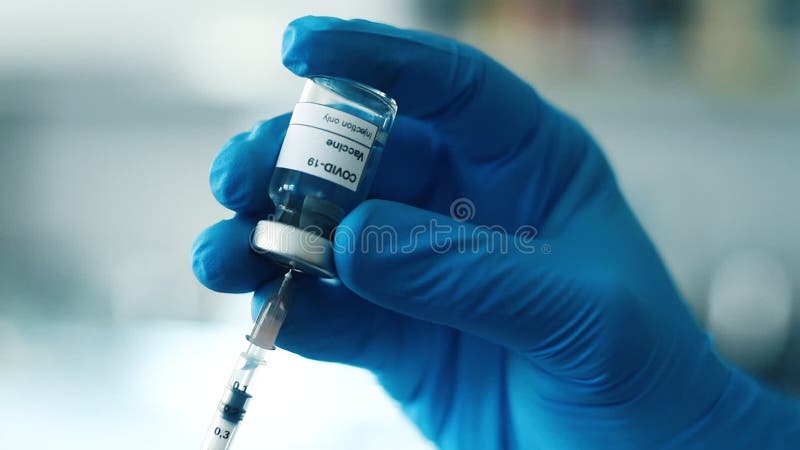 Close up of doctors hands holding a vial to fill a syringe with vaccine stock video footage