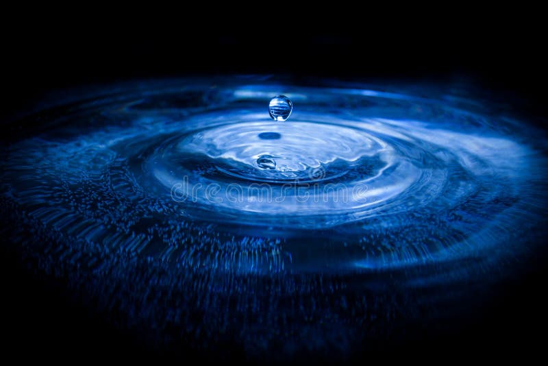 Water drop falling into water making a perfect droplet splash. Water drop falling into water making a perfect droplet splash