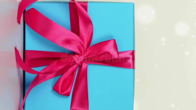 Close-up of an elegant blue gift box with a pink ribbon on a soft white bokeh stock video