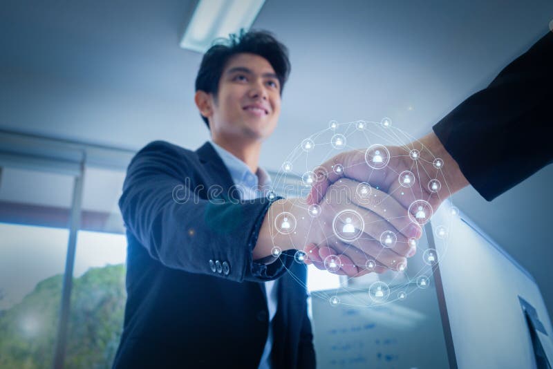 Close-up, energetic young business man shakes hands together to finish the meeting and the social network hologram represents. Business partners. The concept of royalty free stock photos Close-up, energetic young business man shakes hands together to finish the meeting and the social network hologram represents. Business partners. The concept of royalty free stock photos