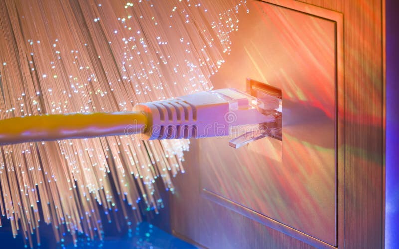 Close-up of an ethernet cable plugged into a wall socket with fiber optical background stock photo