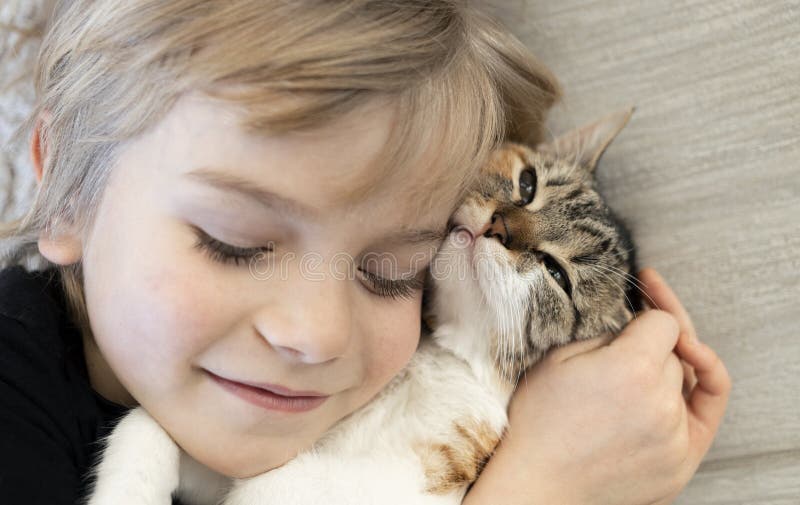 close-up of the face of a boy and a beloved kitten with closed eyes. cat day