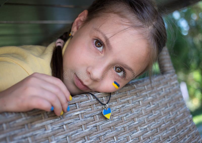 close-up of face of a 7-year-old girl with a painted flag of Ukraine on her cheek