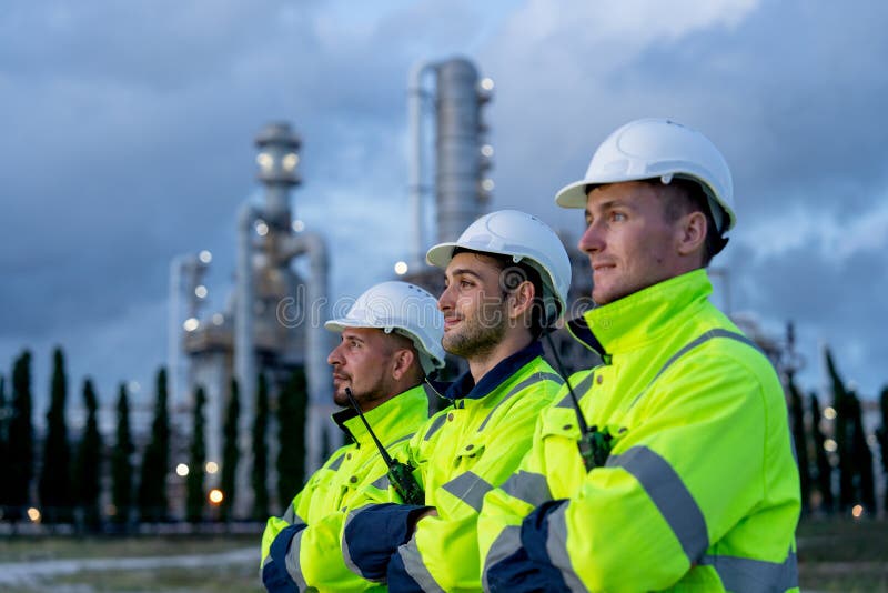 Close up factory engineer or technician workers stand in the row and look to left side with arm-crossed stand in front of refining royalty free stock photo
