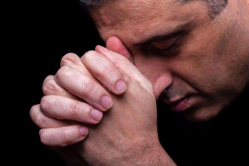 Close up of faithful mature man praying, hands folded in worship to god