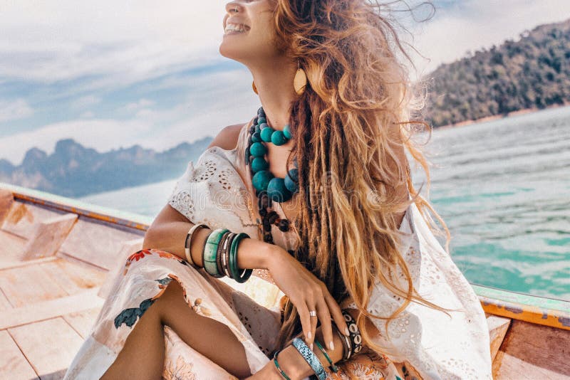 Close up of fashionable young model in boho style dress on boat at the lake