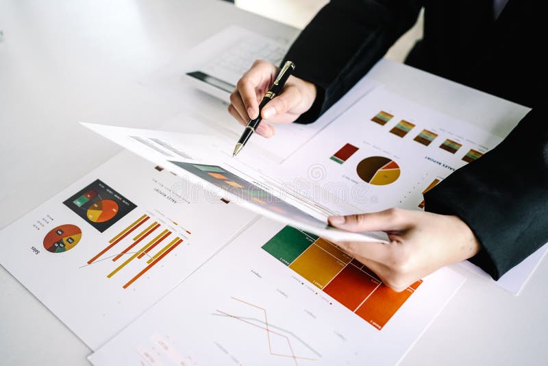 Close-up of female business analyst pointing document graph chart at desk table, above view stock image
