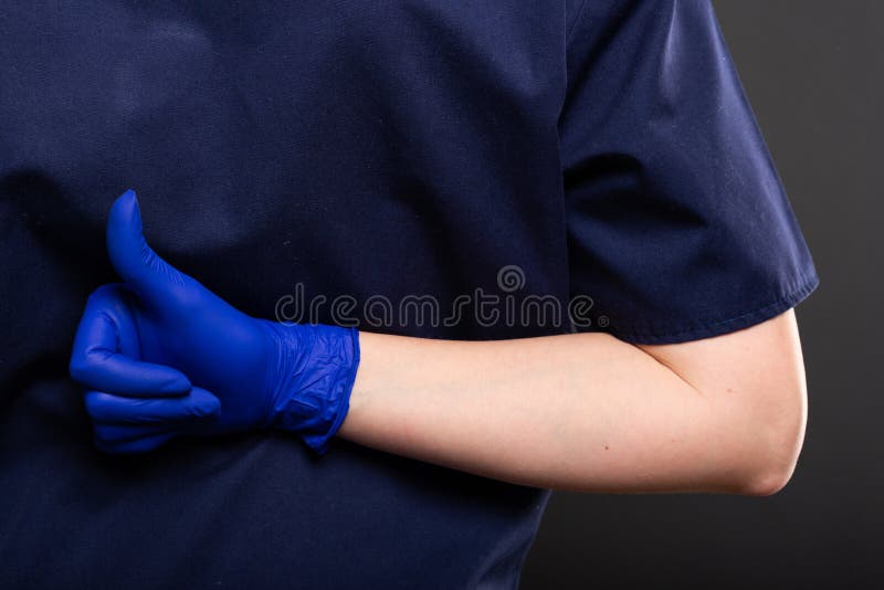 Close-up of female dentist wearing scrubs showing like gesture stock image