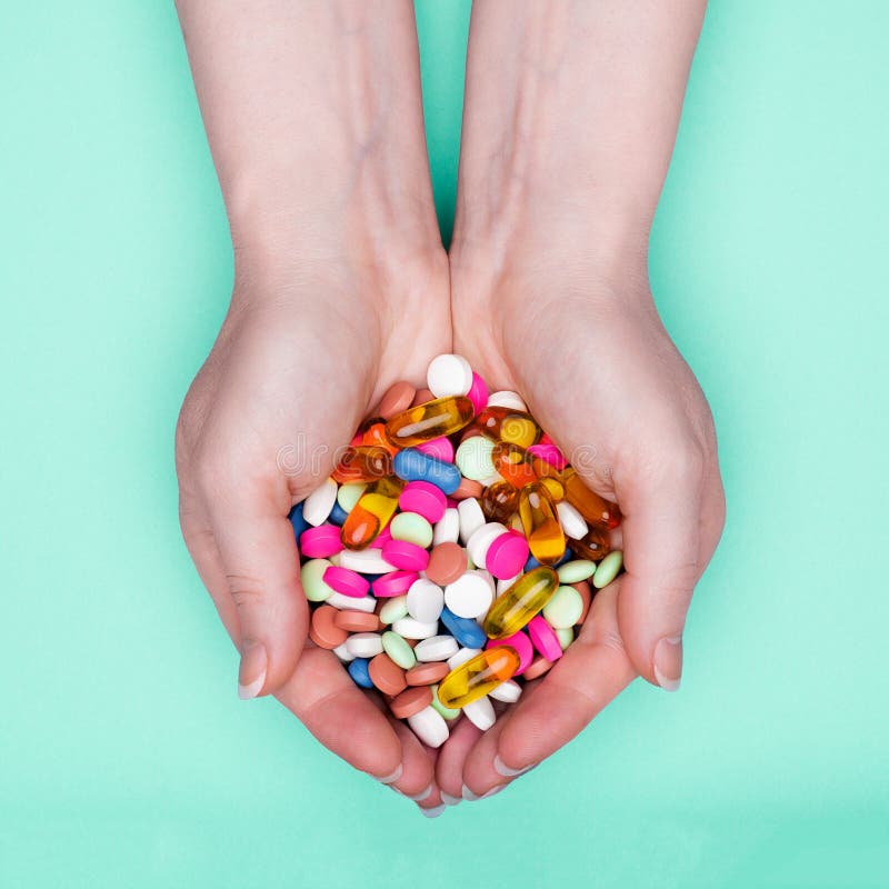 Close up of female hands holding heap of colorful medication pills over pastel blue background. royalty free stock images Close up of female hands holding heap of colorful medication pills over pastel blue background. royalty free stock images