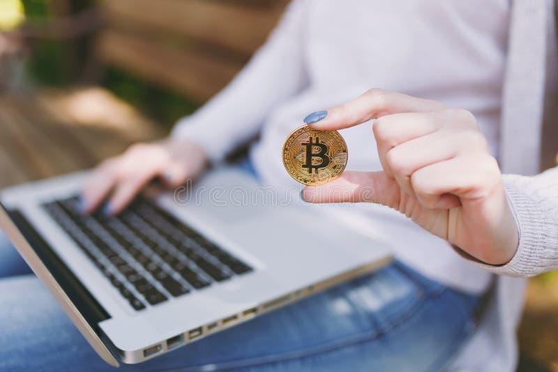 Close up female hands on keyboard. Woman sitting on bench holding bitcoin, coin of golden color, working on modern stock photos Close up female hands on keyboard. Woman sitting on bench holding bitcoin, coin of golden color, working on modern stock photos