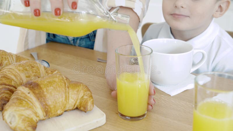 Close-up of female hands pouring orange juice into a glass. Breakfast.