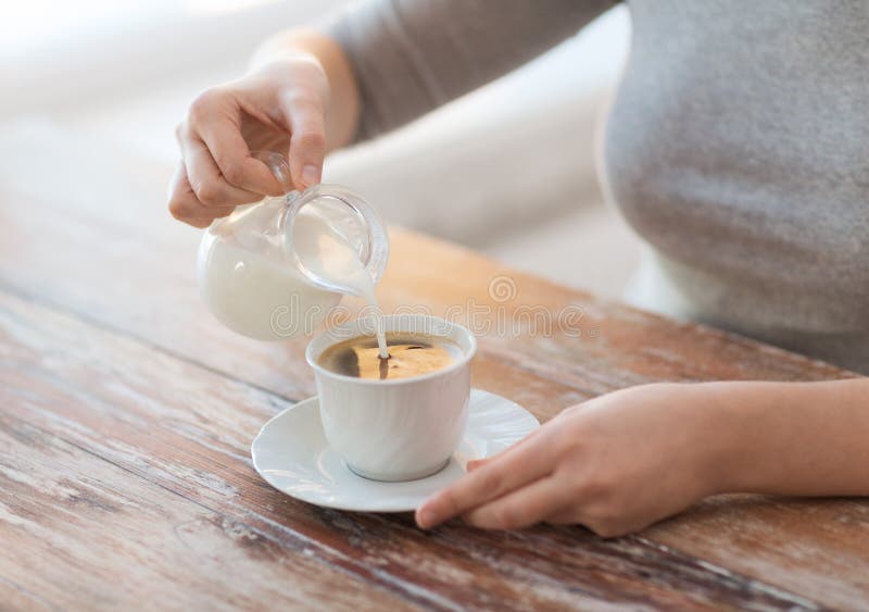 Close up of female pouring milk into coffee stock photo