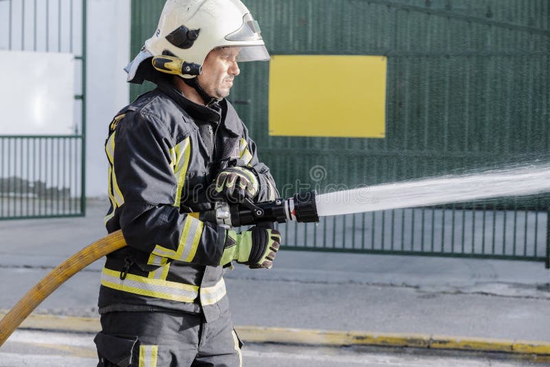 Close-up of a Fireman with a Hose Spreading Water in a Fire Stock Image -  Image of close, occupation: 196443897