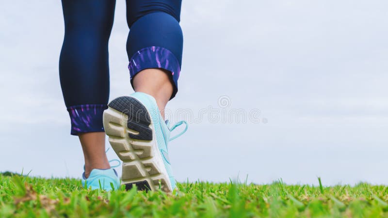 Close up of fitness woman athlete`s running shoes while walking in the park outdoor. Sport, healthy, wellness and active lifestyle background concepts with copy space