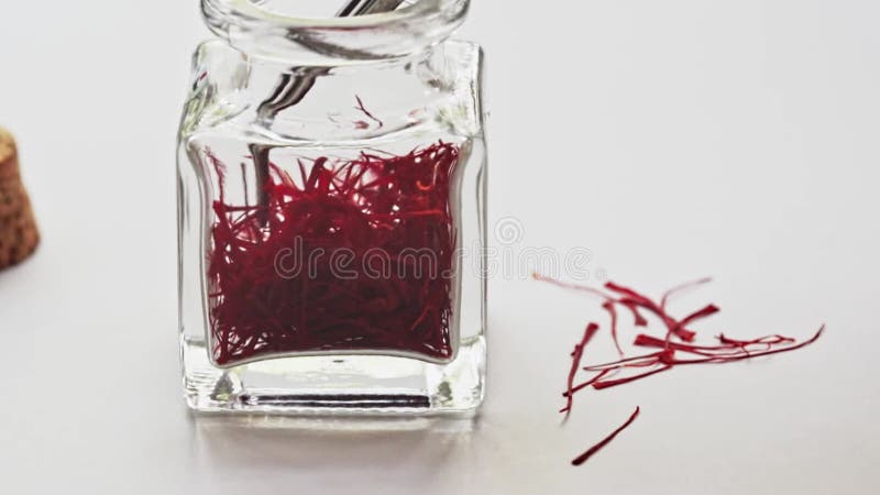 Close up footage of saffron in a glass jar on the rotating table on the white background. stock video