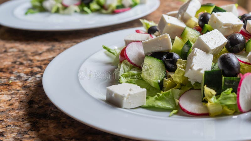 Close up of freshly prepared salad. A close up of a white plate of freshly prepared Greek style salad. Vegetables, olives, feta cheese with out dressing stock image Close up of freshly prepared salad. A close up of a white plate of freshly prepared Greek style salad. Vegetables, olives, feta cheese with out dressing stock image