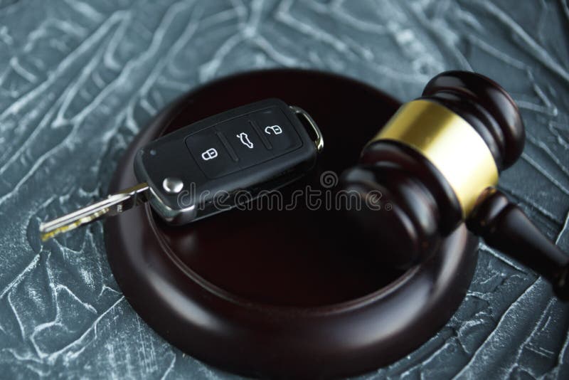 Close-up Of Gavel And Car Key On Sounding Block Against