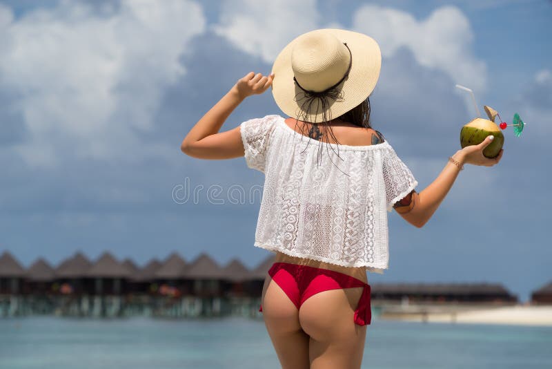 Close up girl back in bikini against ocean beach and coconut