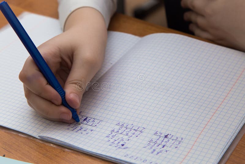 Close-up of a girl& x27;s hand with a ballpoint pen writes numbers in a notebook. stock photography