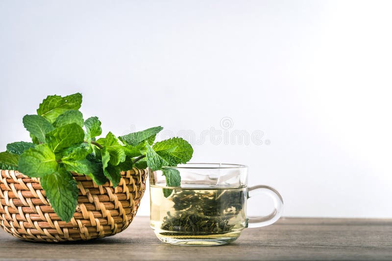 Close up a glass cup of mint tea with green fresh peppermint lea