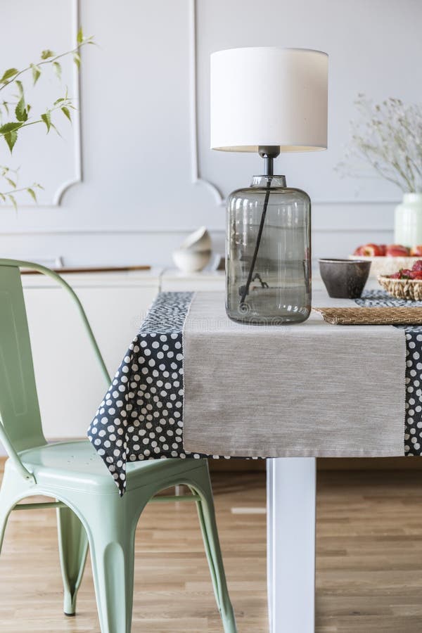 Close-up of a glass lamp on a table next to a green chair in a daily room interior. Real photo royalty free stock image Close-up of a glass lamp on a table next to a green chair in a daily room interior. Real photo royalty free stock image