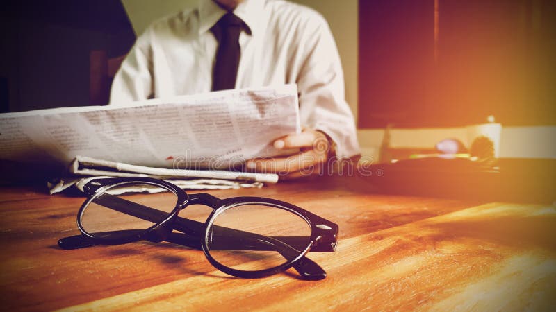 Close up glasses. newsletter concept businessman reading news the newspaper on desk in office
