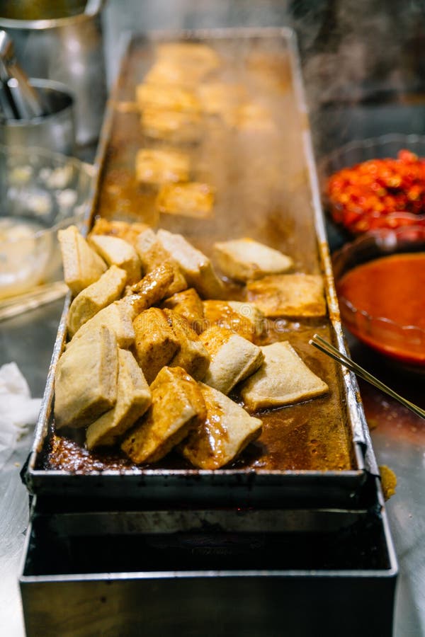 Close-up golden Fermented Tofu or Stinky Tofu on a hot plate with chili pepper spicy sauce, famous Taiwanese signature street food