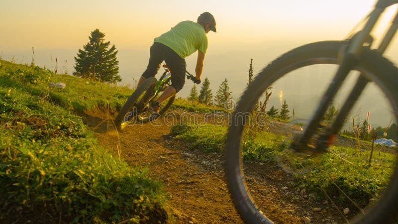 CLOSE UP: Golden sunbeams shine on mountain bikers riding down dirt trail. royalty free stock photos
