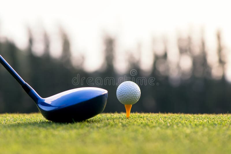 Close up golf ball and driver, player doing golf swing tee off on the green sunset evening time