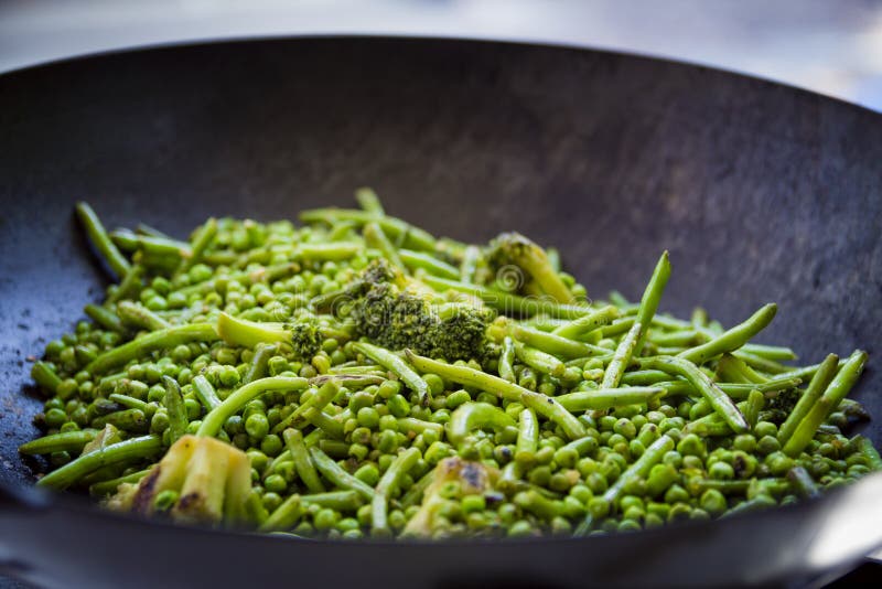 Close Up on Green Beans, Broccoli and Peas are Cooked in a Big Iron Pan