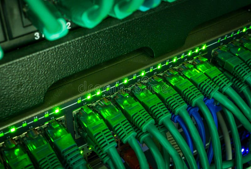 Close up of green network cables connected to switch glowing in the dark stock photo