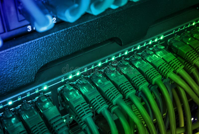 Close up of green network cables connected to switch glowing in the dark stock photo