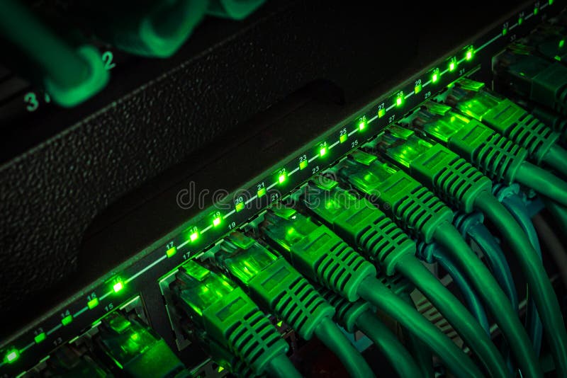 Close up of green network cables from data center connected with patch cord to black switch glowing in the dark royalty free stock photos