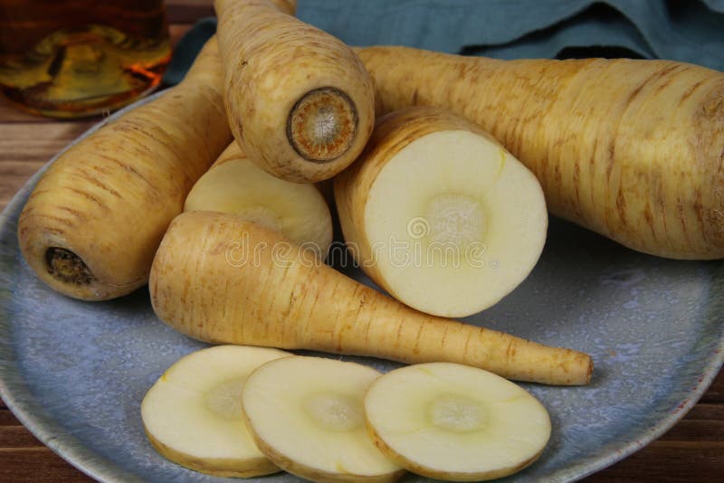 Close up of group raw isolated sliced parsnip root vegetables on blue china plate royalty free stock photos