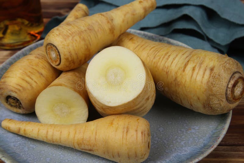 Close up of group raw isolated sliced parsnip root vegetables on blue china plate royalty free stock photo