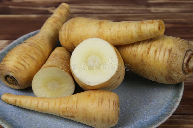 Close up of group raw isolated sliced parsnip root vegetables on blue china plate stock photo