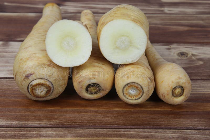 Close up of group raw isolated sliced parsnip root vegetables with wooden background stock image