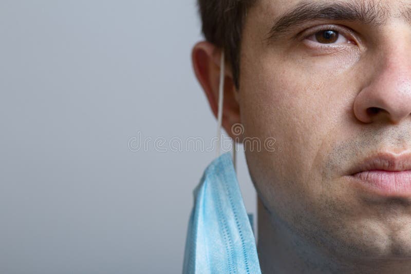 close-up-half-face-exhausted-young-doctor-protective-mask-hanging-ear-difficul-surgery-clinic-gray-studio-176813158.jpg