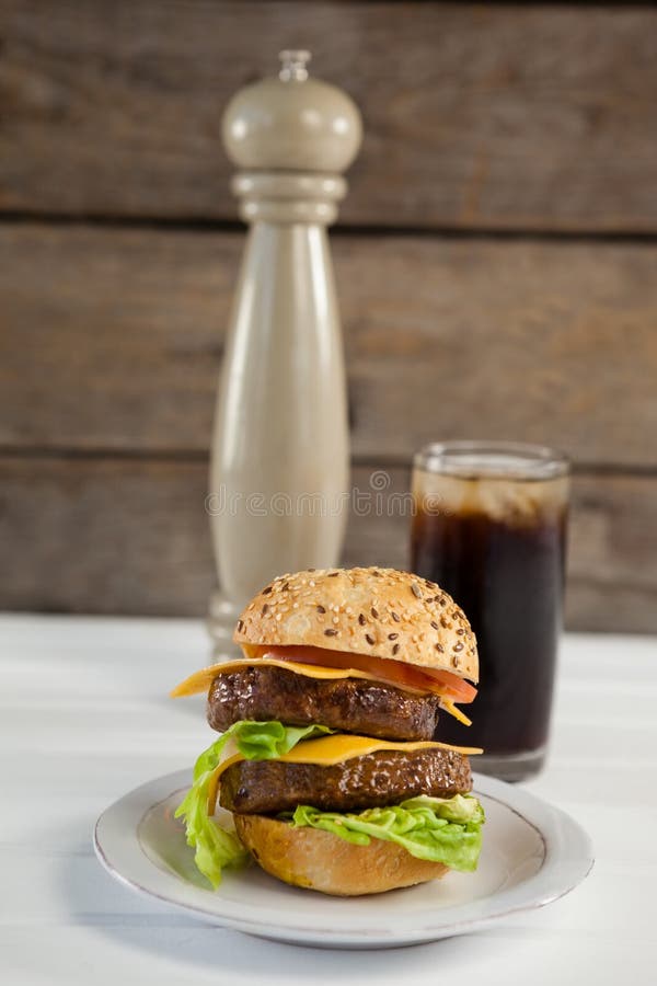 Close-up of hamburger in plate with glass of cold drink royalty free stock photo