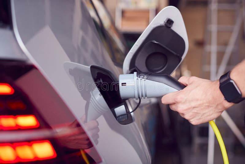 Close Up Of Hand Attaching Power Cable To Environmentally Friendly Zero Emission Electric Car stock photo