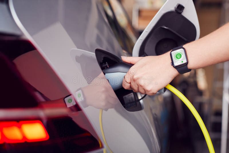 Close Up Of Hand Attaching Power Cable To Environmentally Friendly Zero Emission Electric Car stock photo